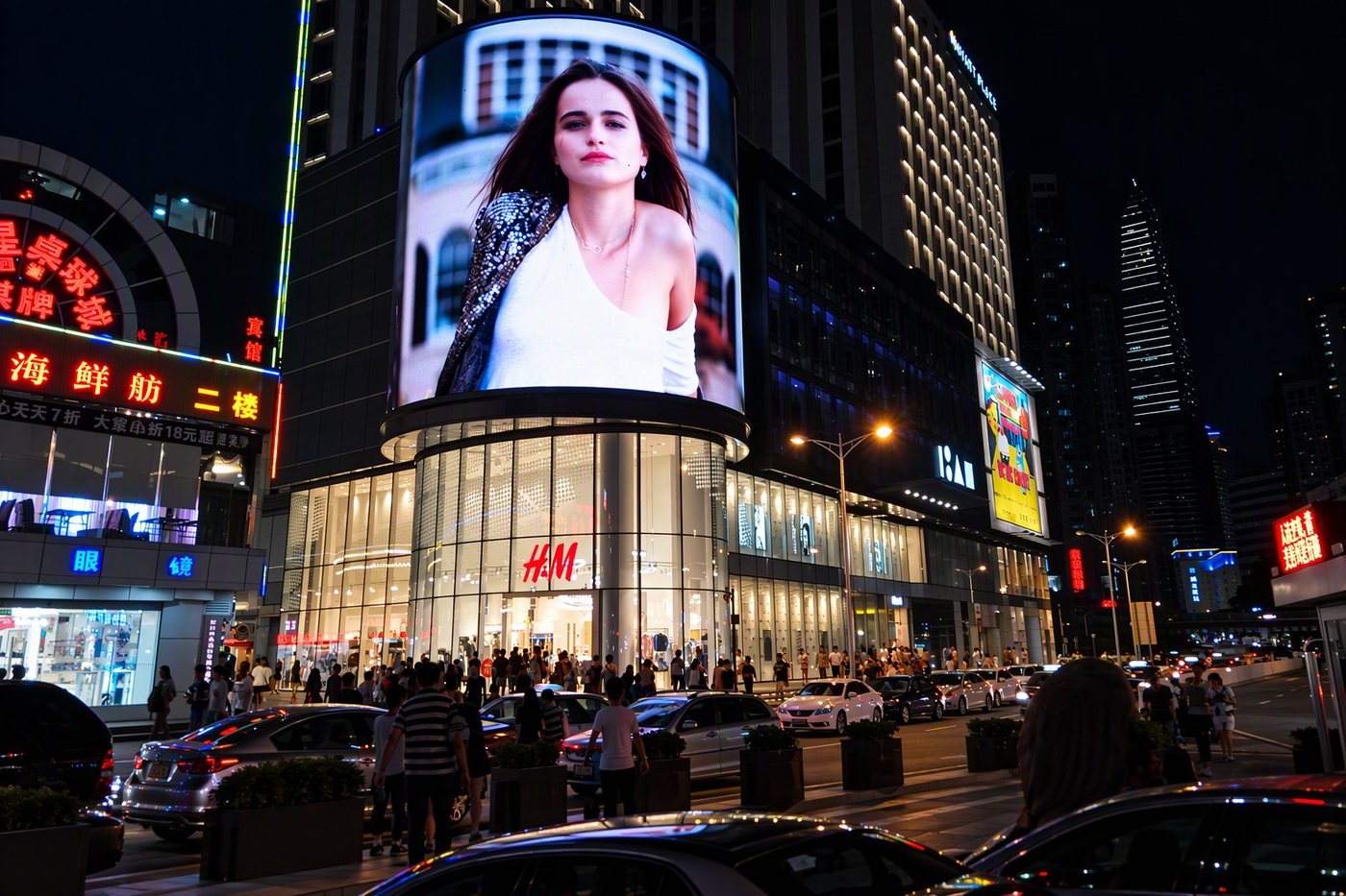 Curved LED screen wrapped around a city storefront at night, with crowds and traffic below