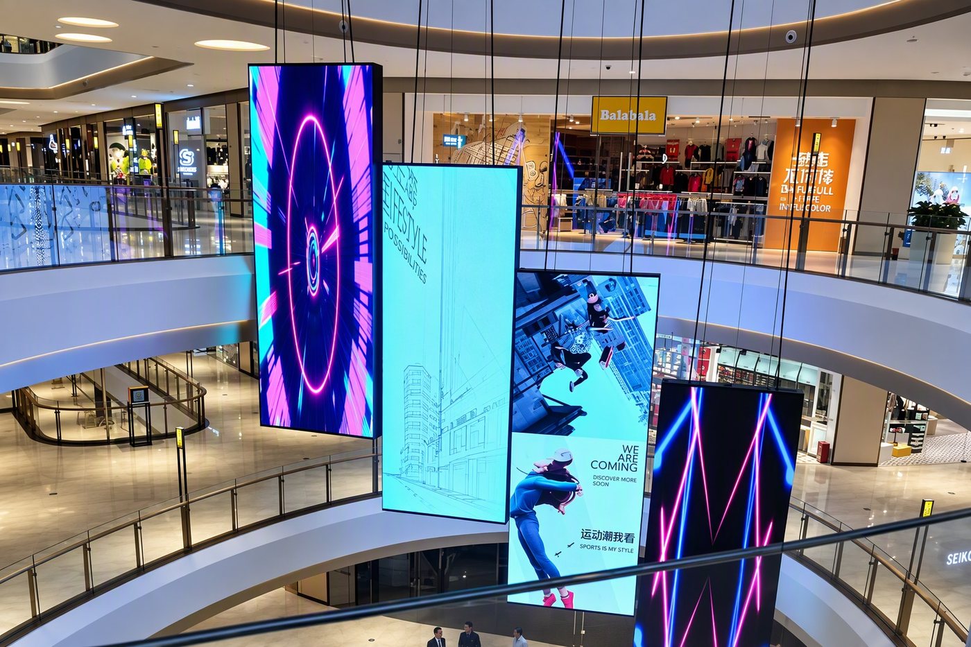 Four tall LED banners suspended in a shopping mall atrium, with retail storefronts behind